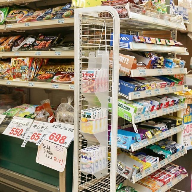 ハンディーハンガーボックスの使用イメージ、棚の横から吊るされボックスの中にお菓子箱が並べられている